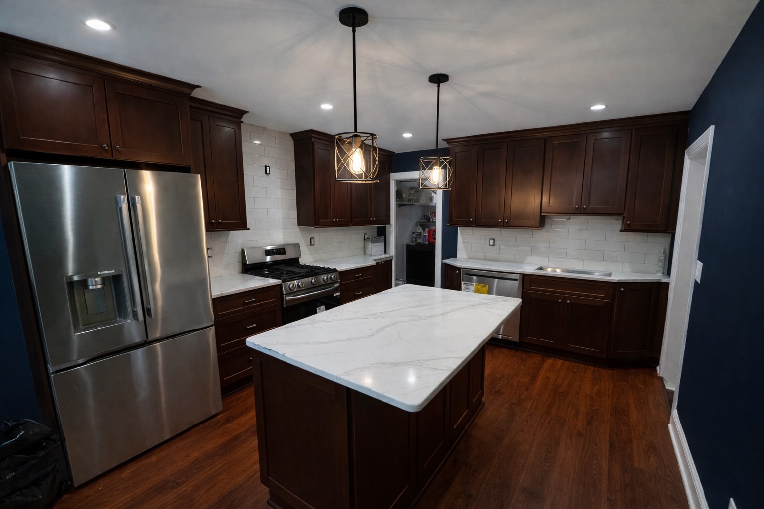 Custom kitchen remodel — dark cabinetry and marble island with pendant lighting