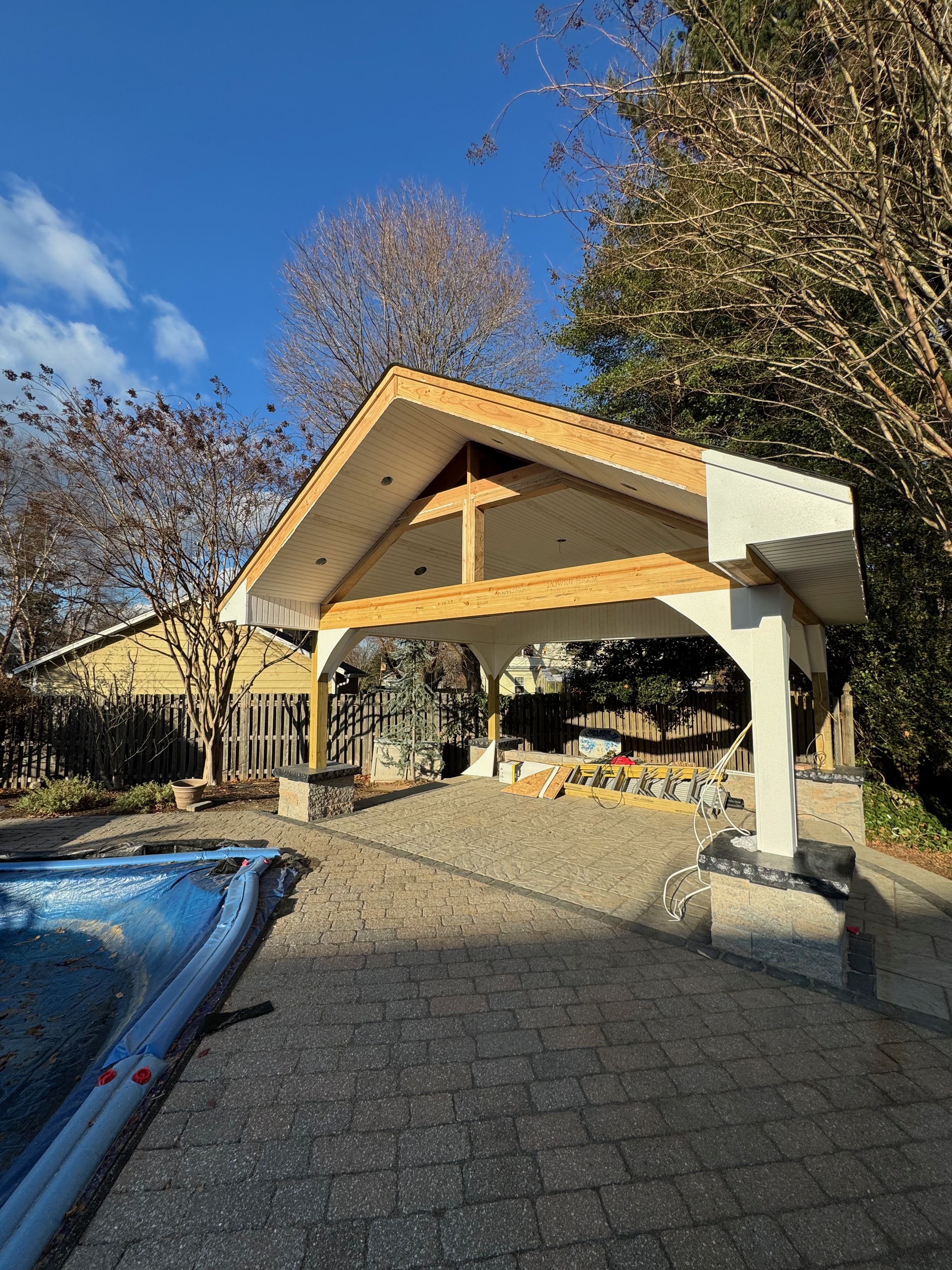 Covered outdoor patio — stone base, white columns, cedar beam ceiling