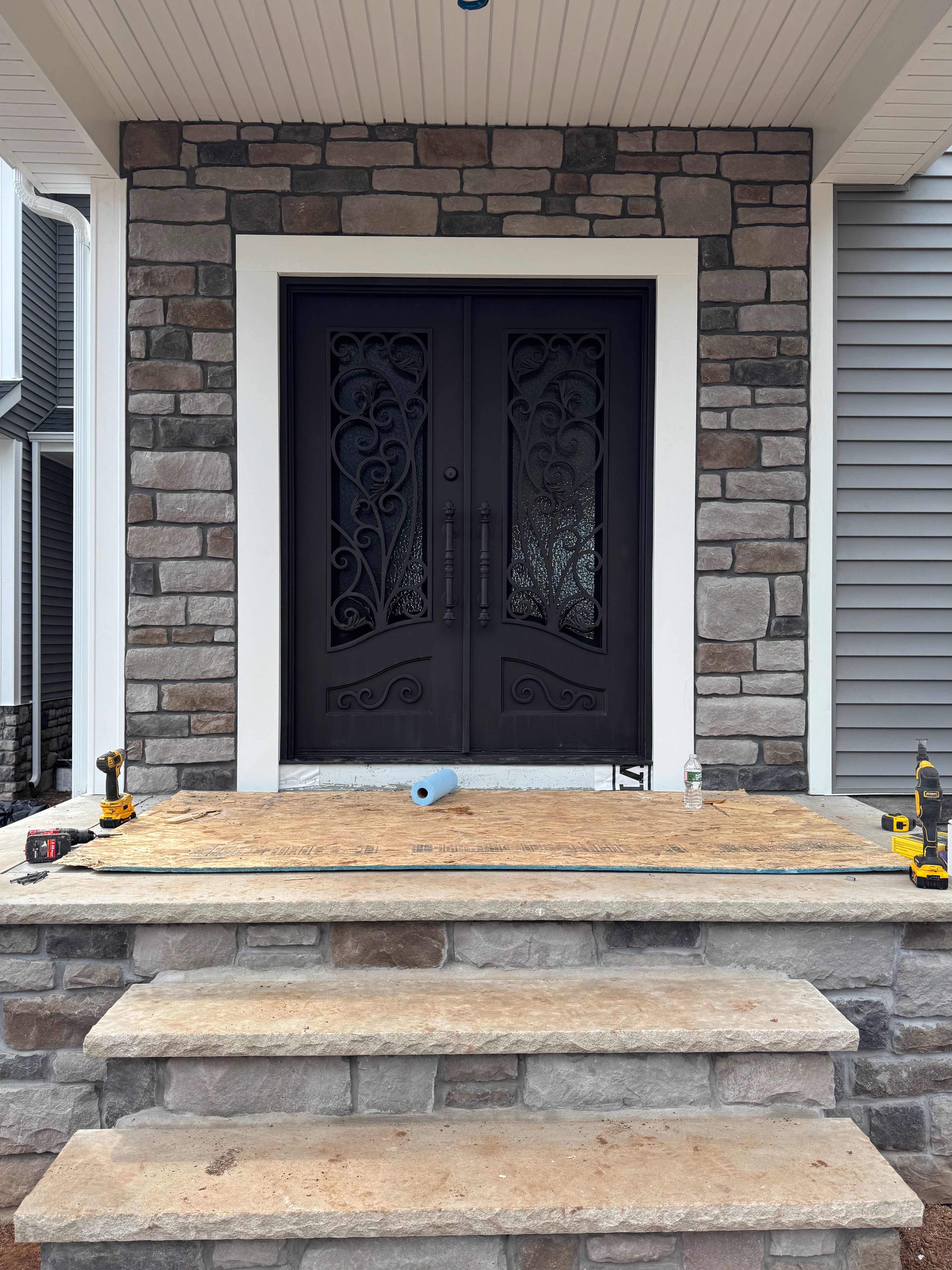Custom entry doors — ornate iron double doors with natural stone surround