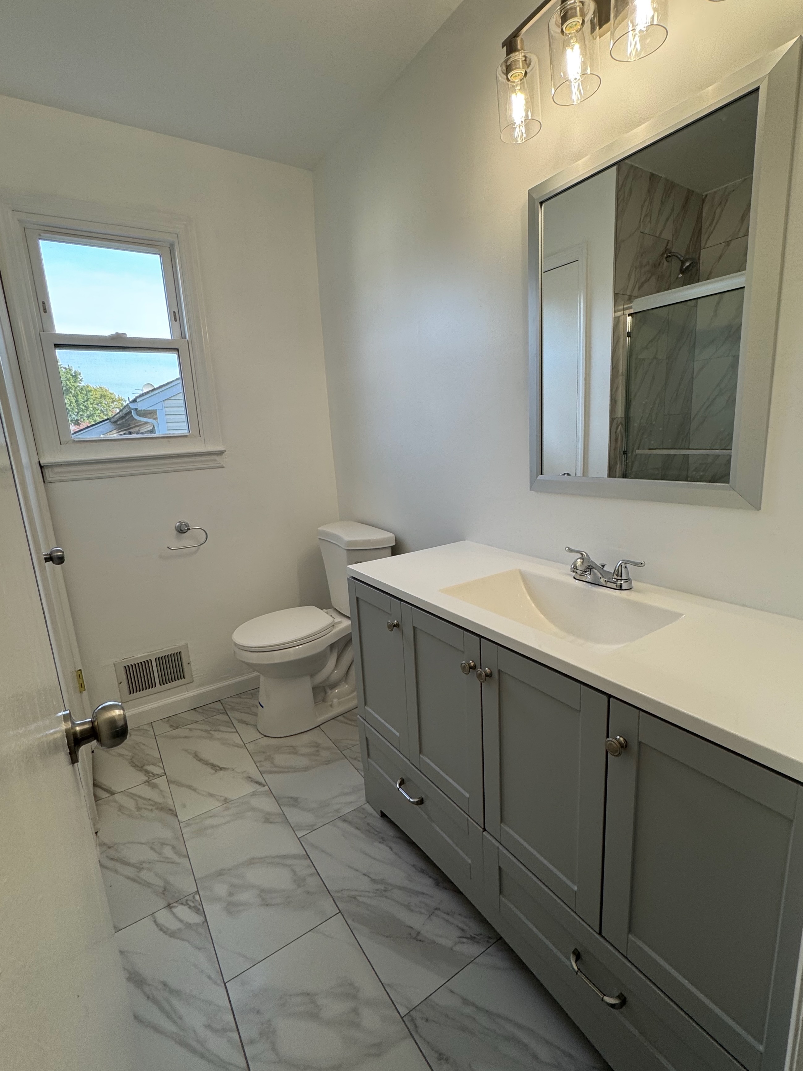 Full bathroom renovation — gray vanity and marble tile floors